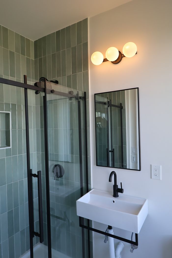 Remodeled bathroom with sage green tile shower and matte black fixtures