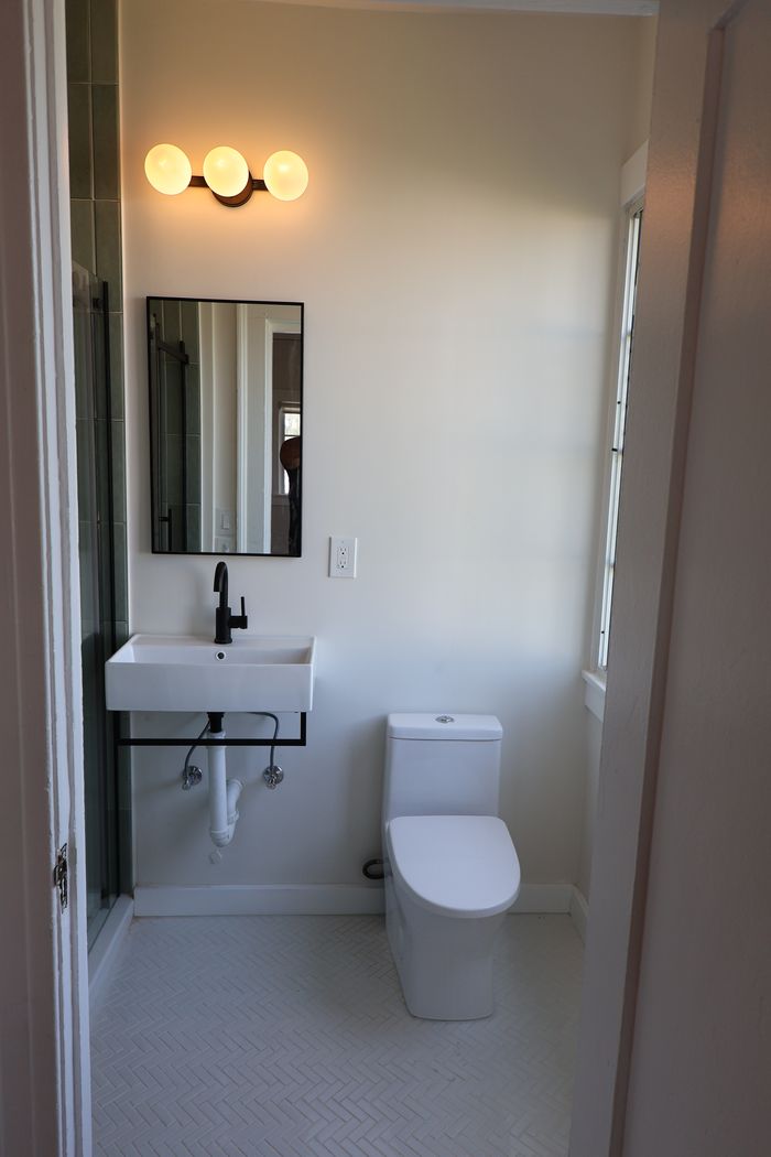 Finished bathroom with wall-hung sink and herringbone tile floor