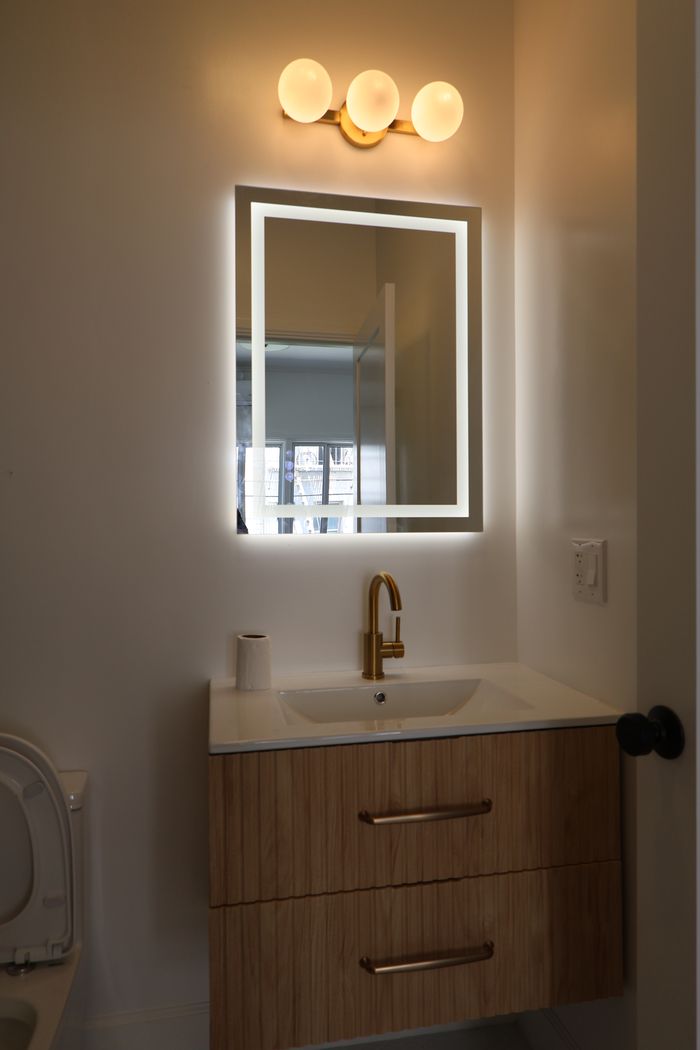 Remodeled powder bathroom with lit mirror and floating wood vanity